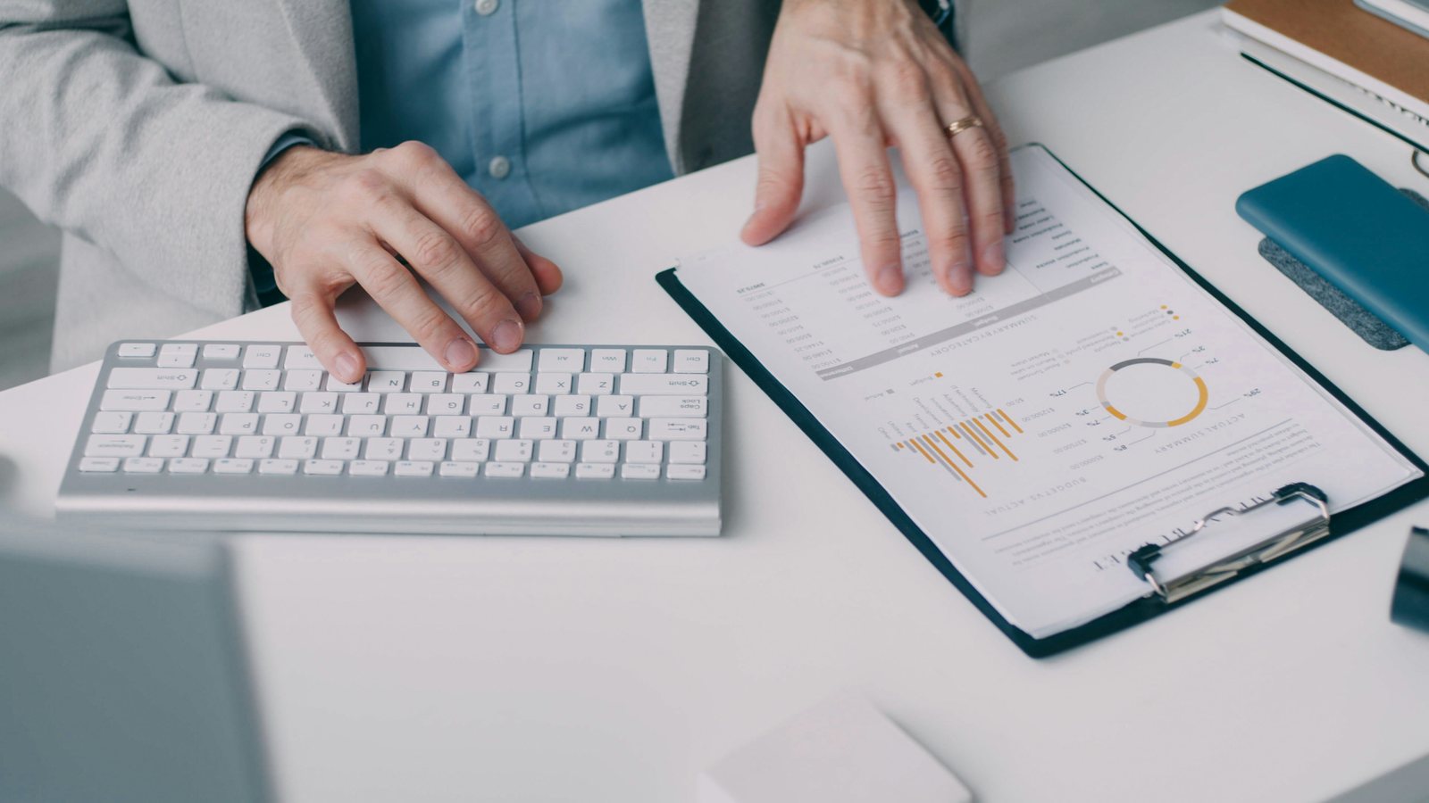 Financial achter een toetsenbord met een rapportage budget versus actual op een klembord