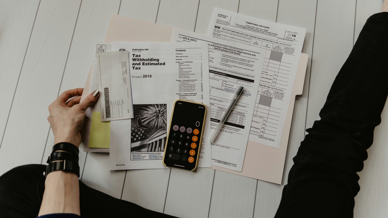 Bureau met formulieren, een rekenmachine en documenten tijdens het doornemen van een dossier
