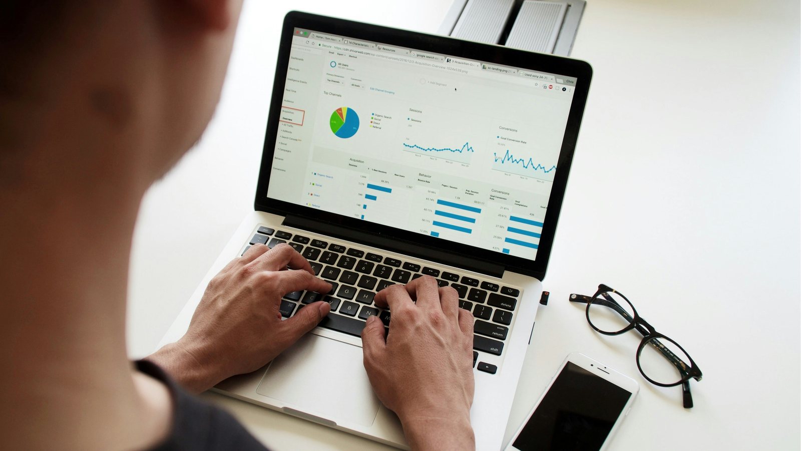 Persoon achter een laptop met een dashboard vol grafieken