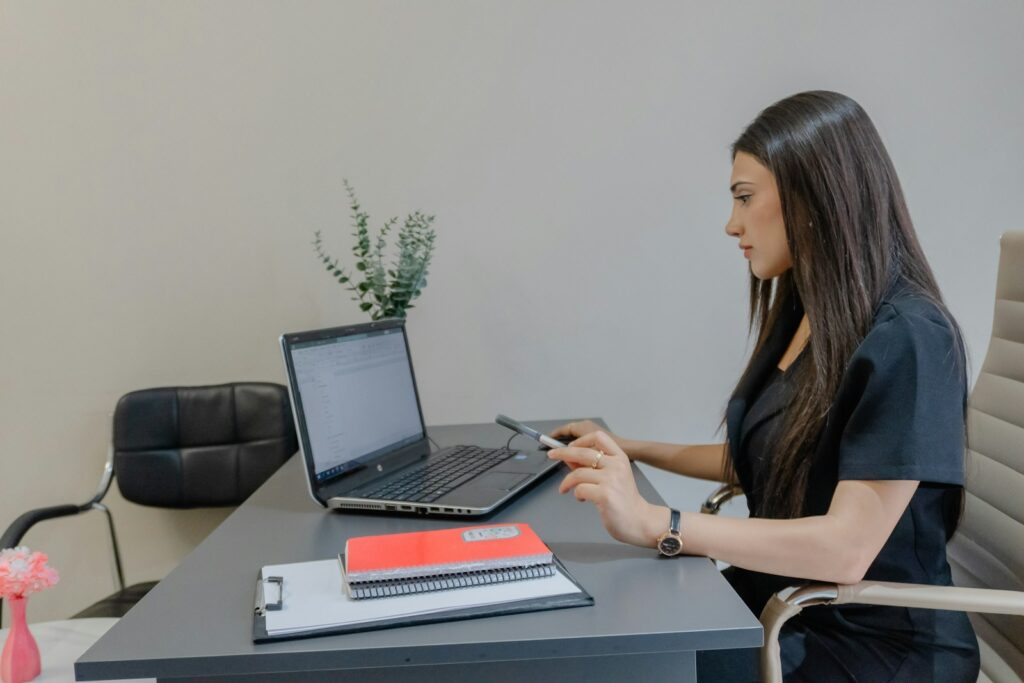 Woman working on a laptop at a desk.